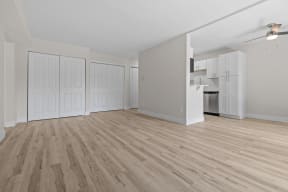 an empty living room with wood flooring and a kitchen
