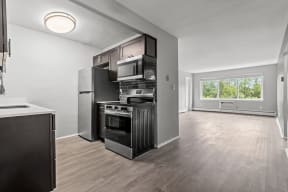 the living room of an apartment with a kitchen and a large window