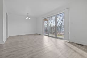 an empty living room with a sliding glass door to a balcony
