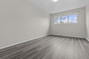 an empty bedroom with wood floors and a window
