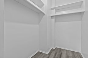 an empty room with white walls and wooden floors and a white closet with a window