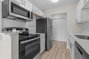 a renovated kitchen with stainless steel appliances and white cabinets