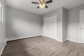 an empty living room with a ceiling fan and a closet