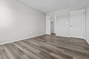 the living room of an apartment with white walls and wood flooring