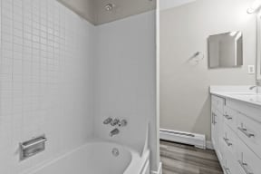 a white bathroom with a tub and a sink and a mirror