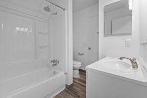 a white bathroom with a tub and a sink and a toilet