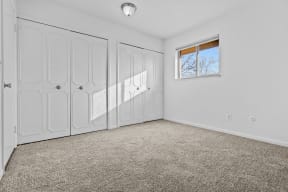 an empty room with white walls and white closets and a window