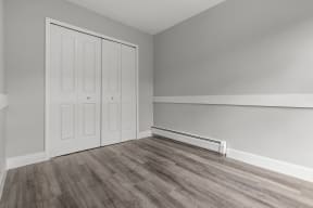 an empty room with wood flooring and white walls and doors