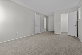 the living room of an apartment with carpeting and white doors