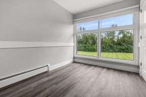 an empty room with a large window and wood floors