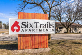 a sign for six trails apartments in front of a parking lot