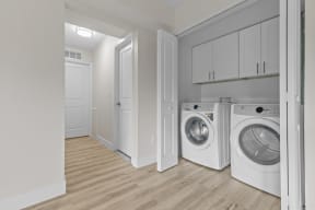 a washer and dryer in a laundry room with white cabinets