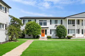 the view of an apartment building with a green lawn and a orange door