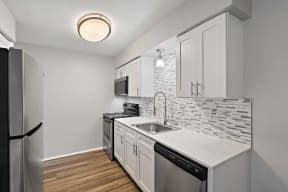 a renovated kitchen with white cabinets and a stainless steel refrigerator