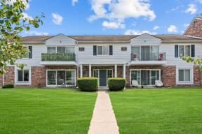 a large white house with green grass in front of it at Apple Ridge Apartments - Livonia, MI, Livonia