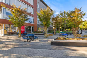 a courtyard with picnic tables and benches in front of a brick building