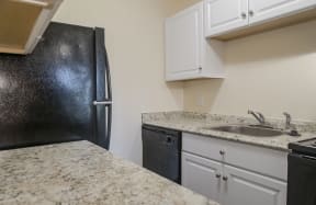 a kitchen with granite counter tops and a black refrigerator