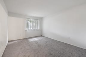 an empty room with a window and white walls