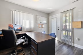 a home office with a desk and a window with blinds