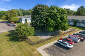Aerial view of a parking lot with cars in front of a house at Town & Country Apartments - Wixom, MI, Michigan