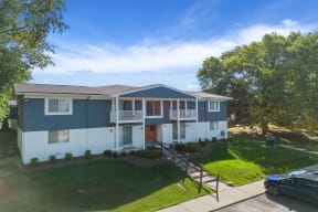 a blue and white house with a yard and trees at Town & Country Apartments - Wixom, MI, Wixom, Michigan