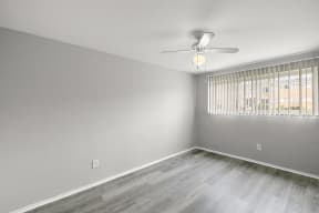 an empty bedroom with a window and a ceiling fan