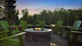 A fire pit surrounded by green chairs on a patio.