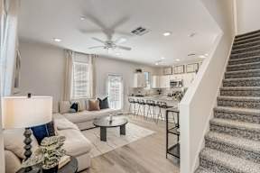 A living room with a staircase leading to the second floor.