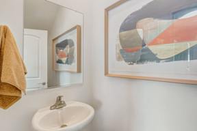 A bathroom with a white sink and a framed artwork on the wall.