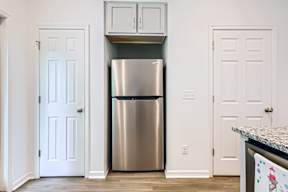 A kitchen with a stainless steel refrigerator and white doors.