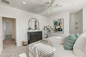 A bedroom with a white bed and a black dresser.