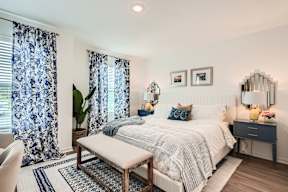A bedroom with a bed, nightstand, and a mirror on the wall.