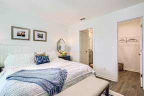 A bedroom with a bed, a bench, and two pictures on the wall.