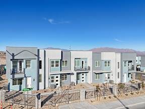 A row of modern houses with blue and grey exteriors are shown in a residential area.