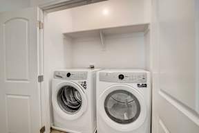 Two white front loading washing machines in a small laundry room.