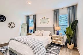 A bedroom with a bed, nightstand, and a plant.