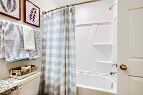 A white bathroom with a blue and white checkered shower curtain.