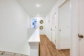 A hallway with a white door and a clock on the wall.