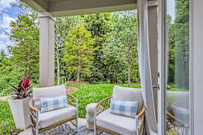 Two chairs with blue and white pillows sit on a porch.