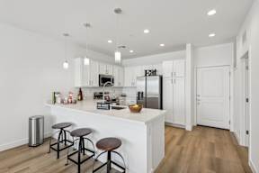 A kitchen with white cabinets and a white island with a counter top.