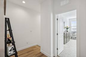 A white hallway with a doorway leading to a living room.