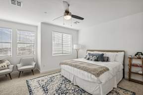 A bedroom with a large bed, a chair, and a ceiling fan.