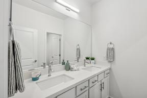A bathroom with a white sink and a striped towel hanging on the door.