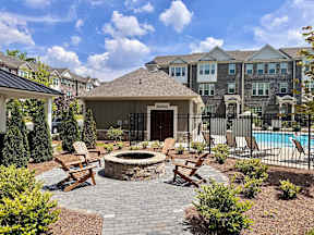 an outdoor patio with a fire pit and chairs in front of an apartment building