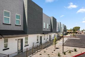 A row of modern houses with a parking lot in front.