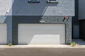 A modern house with a garage door and a red light on the wall.