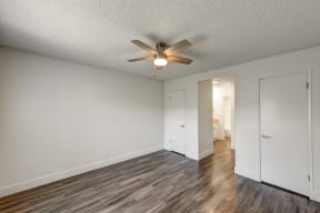 an empty bedroom with a ceiling fan and wood flooring
