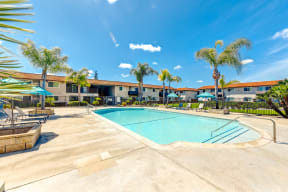 a swimming pool with palm trees and a building in the background