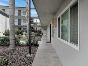 A long concrete walkway leads to a building with a balcony.