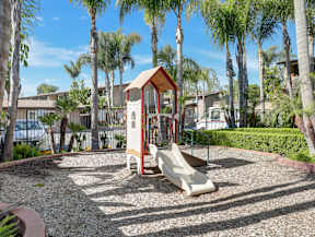 A playground with a red and white structure and a slide.